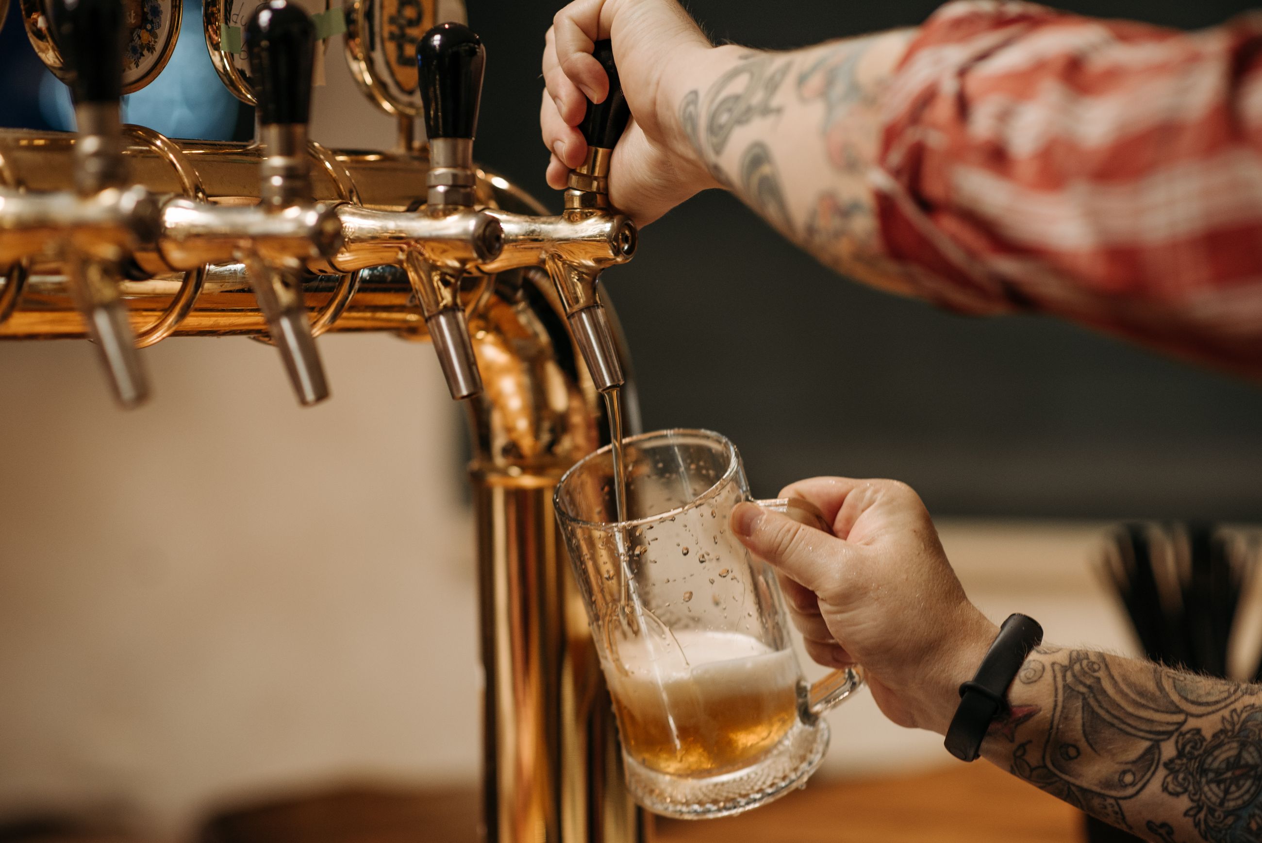 Bartender som tapper øl fra en tappekran i messing