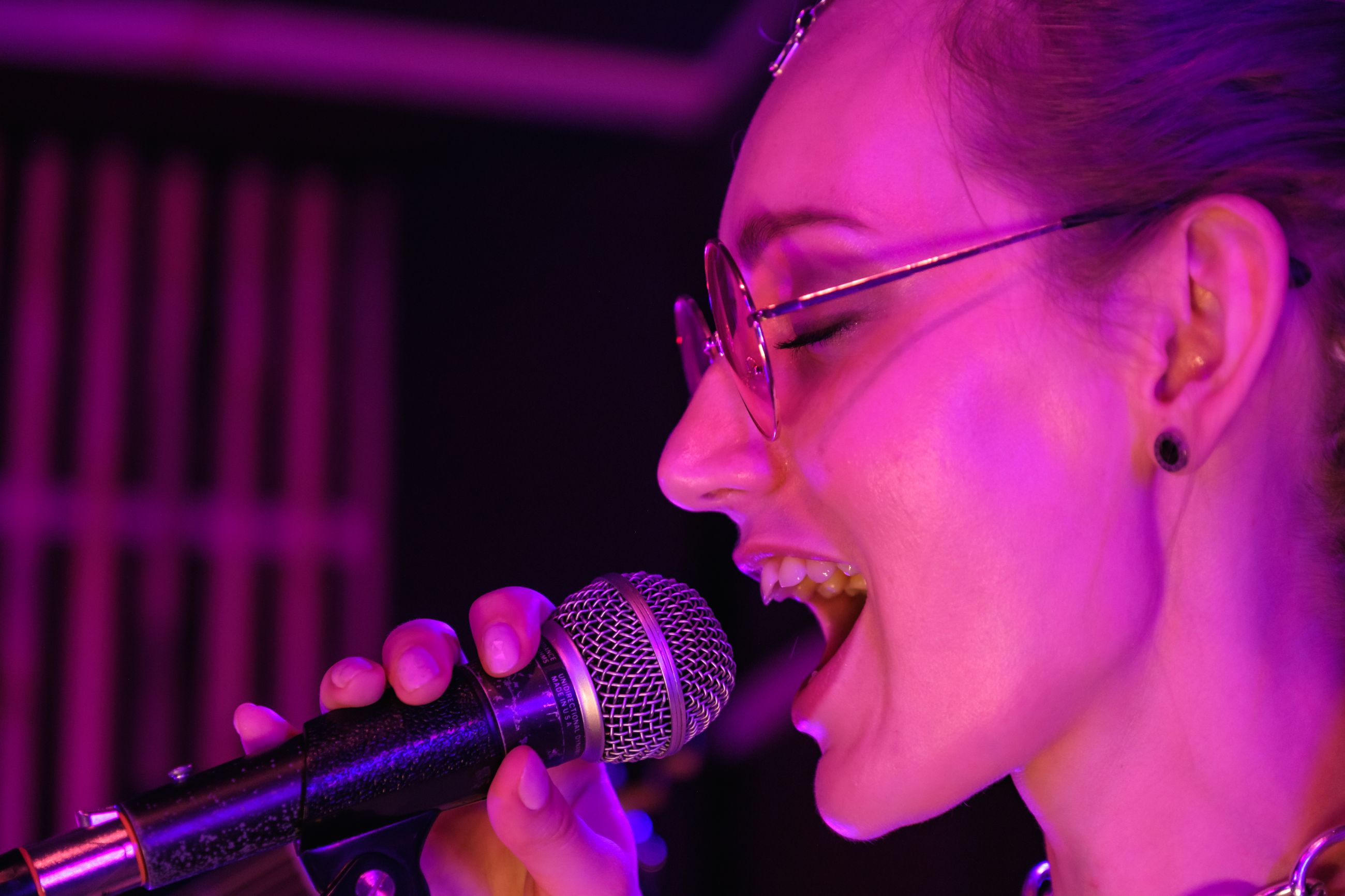 Kvinne som synger karaoke i rosa lys