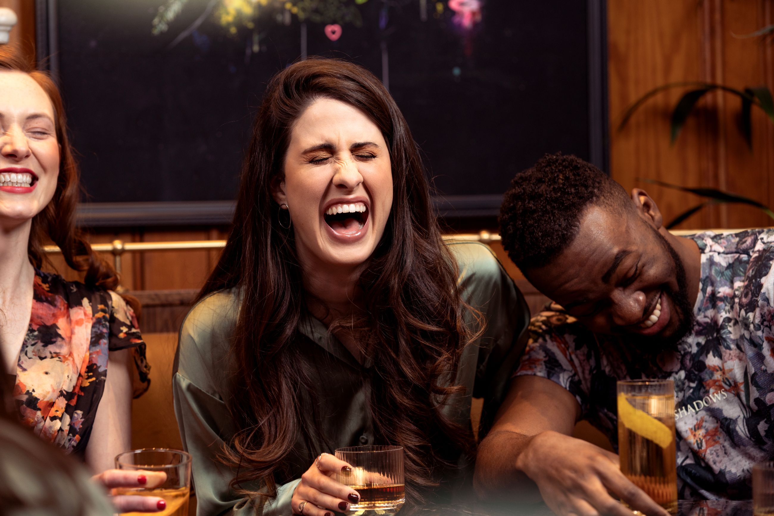 Venner som ler med drinker i hendene i en bar